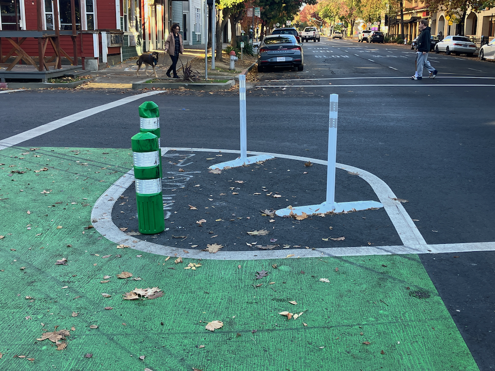 photo of turn wedge at 16th St & P St, with green K-71 delineators and rubber speed bumps